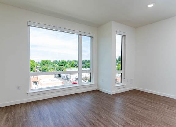 A room with a large window and wooden flooring.