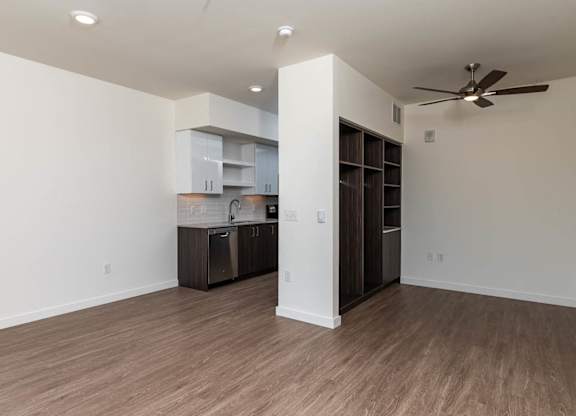 A room with a ceiling fan and a kitchenette.