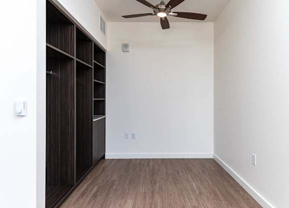 A room with a ceiling fan and wooden flooring.