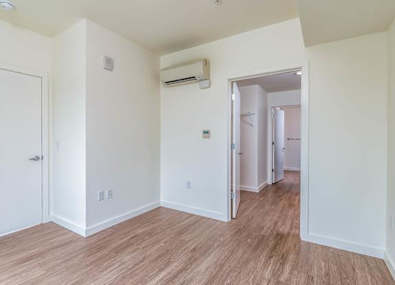 A room with a white door and a white wall with a window.