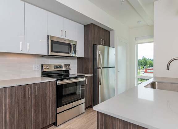 A modern kitchen with a white countertop and stainless steel appliances.