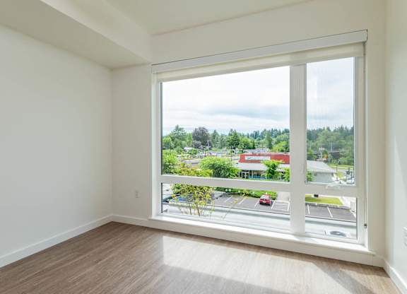 A room with a large window overlooking a parking lot and buildings.