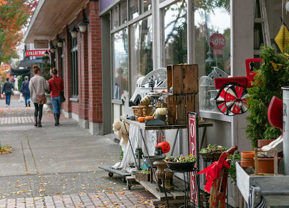 A street scene with a woman walking past a storefront with a sign that says