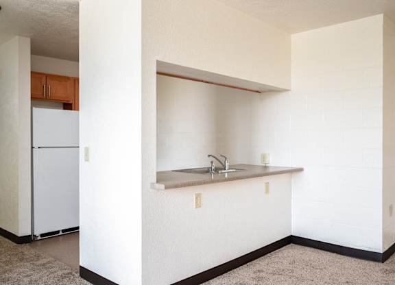 an empty kitchen with a sink and a refrigerator