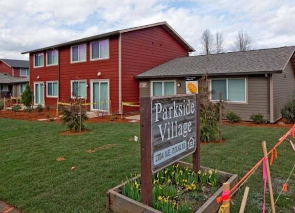 A sign that says Parkside Village stands in front of a building.