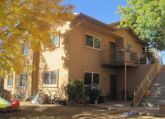 A yellow tree is in front of a tan house.