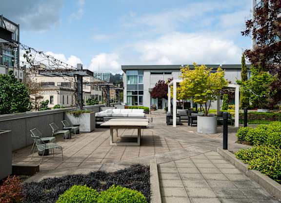 A patio with a table and chairs surrounded by greenery.
