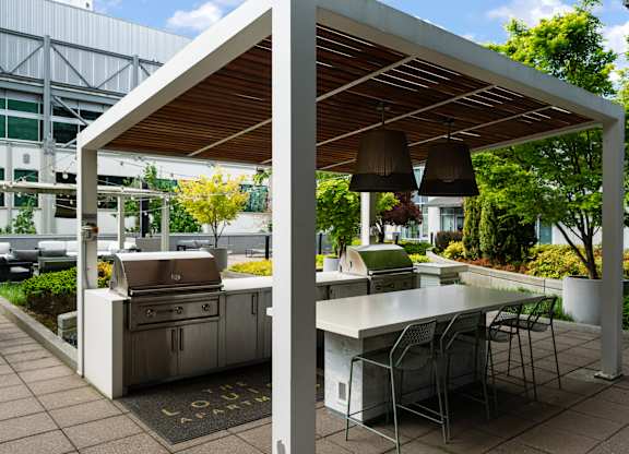 A white outdoor kitchen with a grill and table.