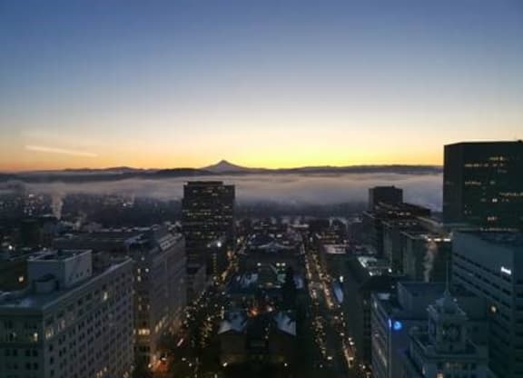 A cityscape at dusk with a mountain in the distance.