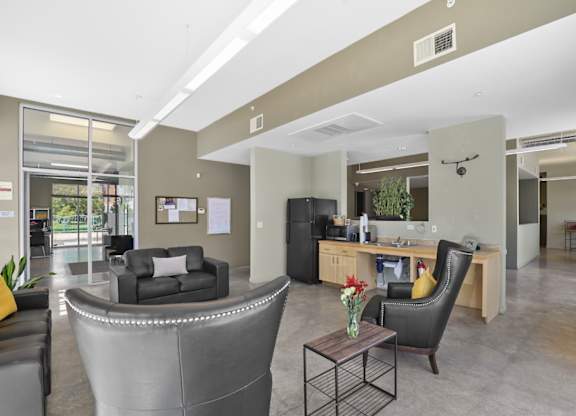 A modern office space with a curved grey desk and a black leather couch.