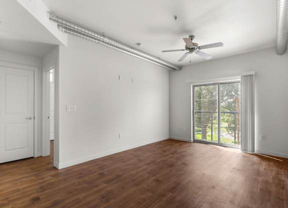 A room with a ceiling fan and sliding glass doors.