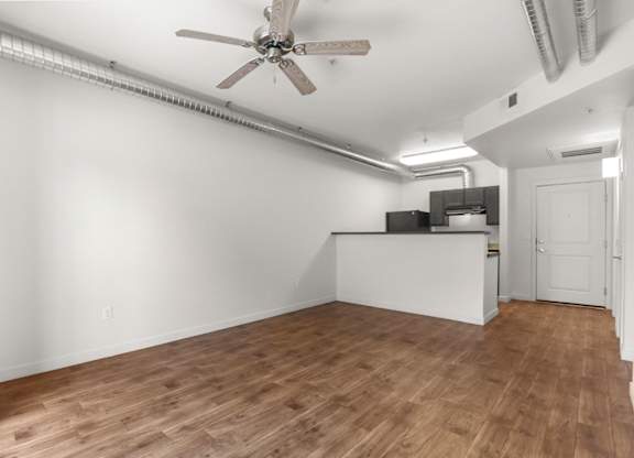 A room with a ceiling fan and wooden flooring.