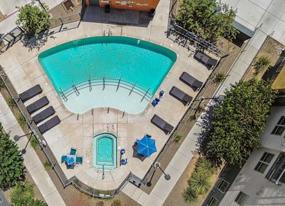 A swimming pool surrounded by lounge chairs and trees.