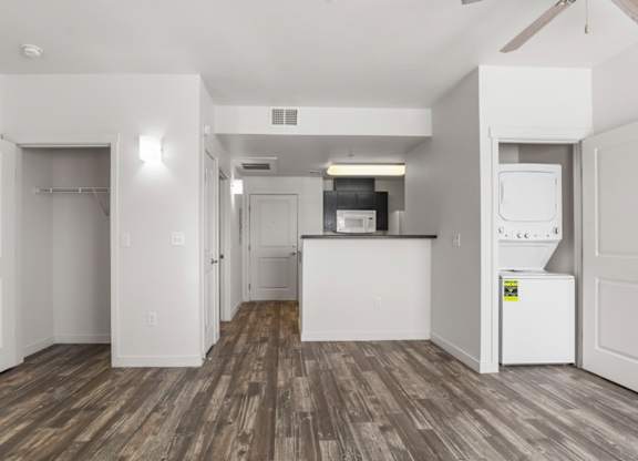 A kitchen with white appliances and wood flooring.