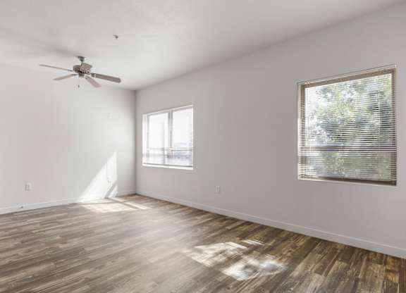 A room with a ceiling fan and a window with blinds.