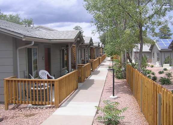 A row of houses with wooden fences and a sidewalk.