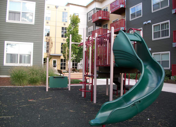 a playground with a slide in front of an apartment building