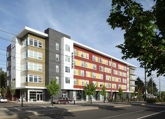 A modern multi-story apartment building with a mix of grey, white, and red exterior colors.