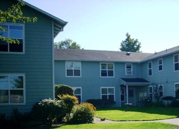 Apartment complex with green lawn and trees in the background.