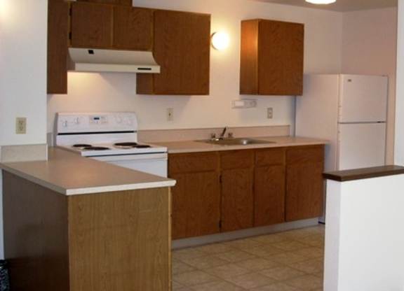 A kitchen with wooden cabinets and a white fridge.