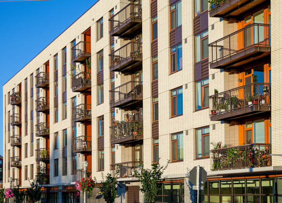 A tall building with balconies and windows in various colors.