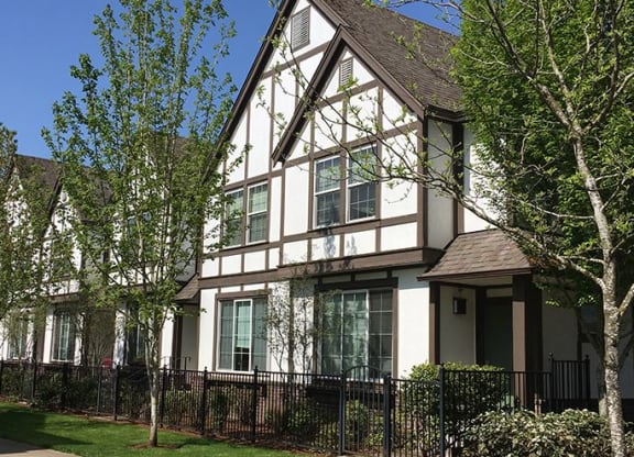 a house with a fence and trees in front of it