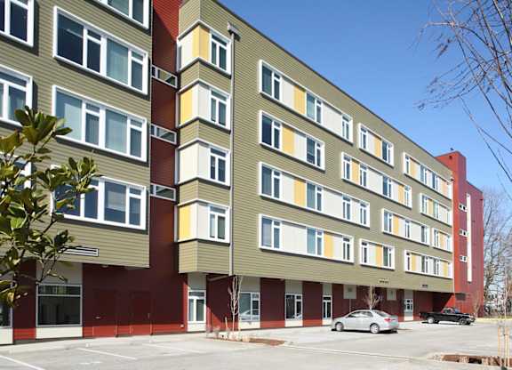 A multi-story building with a parking lot in front.