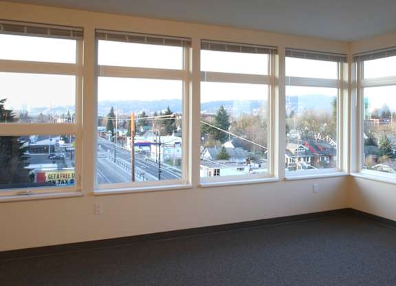A room with large windows overlooking a city street.