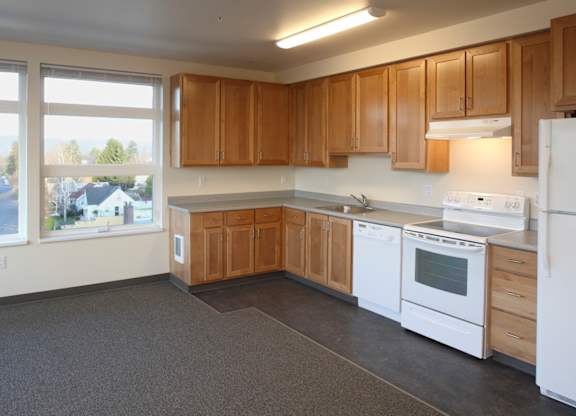 A kitchen with white appliances and wooden cabinets.