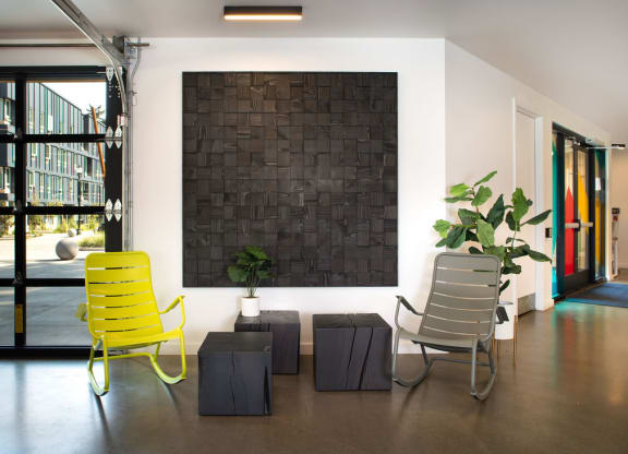 a black brick wall in the middle of a room with two yellow chairs in front of it