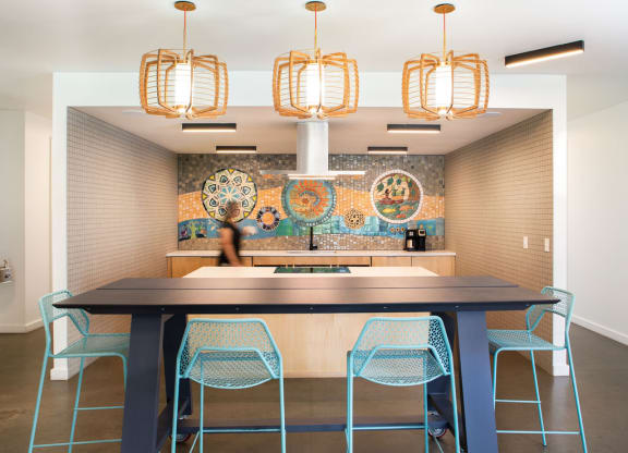 a large table with blue chairs in front of a mosaic wall