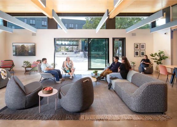 people sitting in a living room with couches and chairs