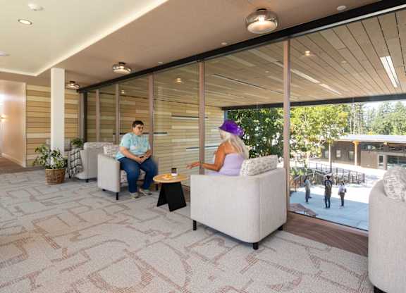 Two people sitting on a couch in a room with a tiled floor.