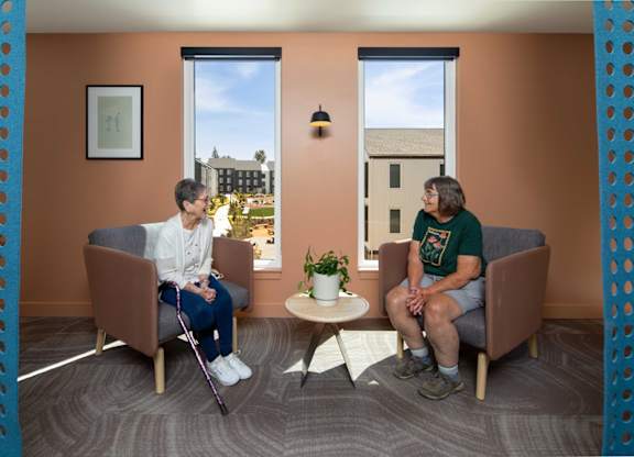 Two people sitting in a room with orange walls.