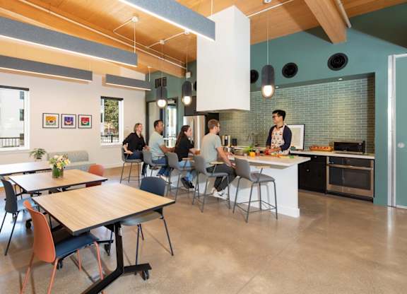 A group of people are sitting around a table in a modern kitchen.