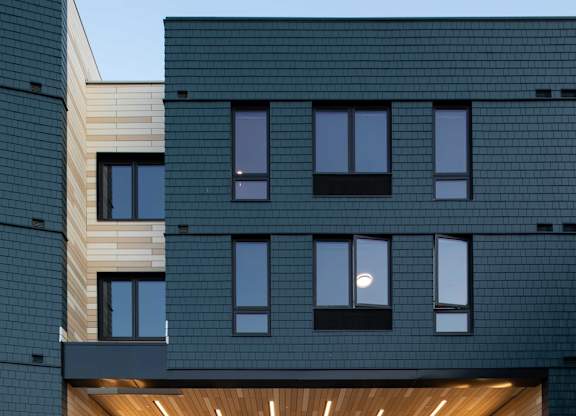 A modern building with a black facade and a wooden entrance.