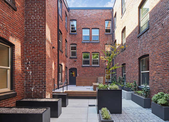 A courtyard with a brick building and a black door.