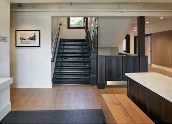 A black and white photo hangs on a white wall above a black staircase.