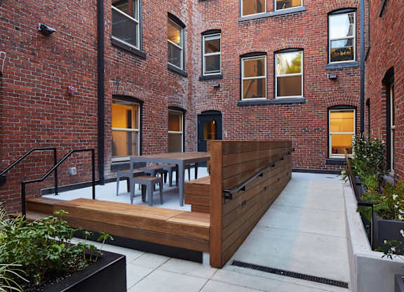 A patio with a table and chairs is surrounded by a brick building.
