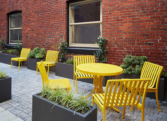 A yellow chair is placed in front of a red brick wall.