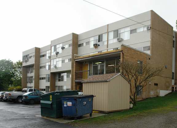 A large apartment building with a dumpster in front of it.