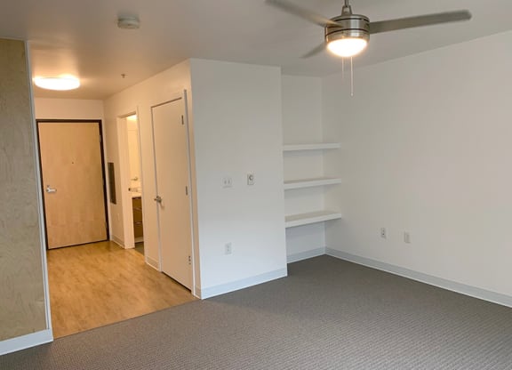 a bedroom with white walls and a ceiling fan