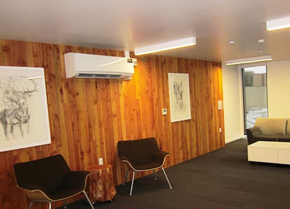 a living room with a wooden wall and a couch and chairs
