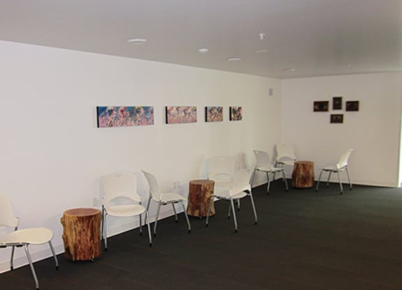 a room with white chairs and tables and pictures on the wall