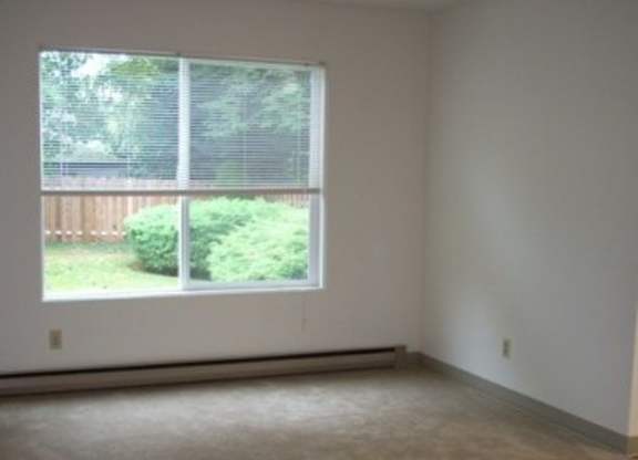A room with a large window and a view of a green lawn and a wooden fence.