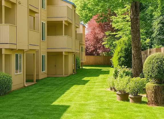 A long grass lawn in front of apartment buildings.