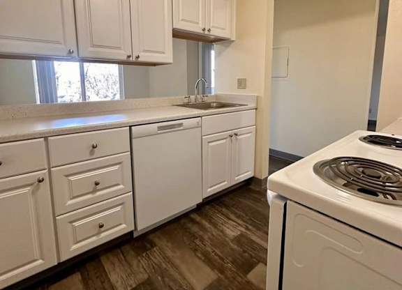 A kitchen with white cabinets and a white dishwasher.
