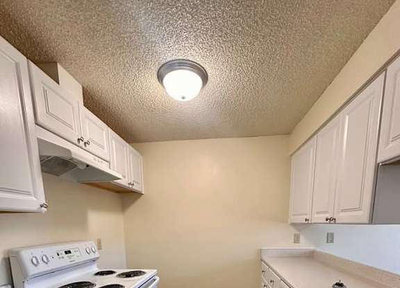 A kitchen with white cabinets and a stove top oven.