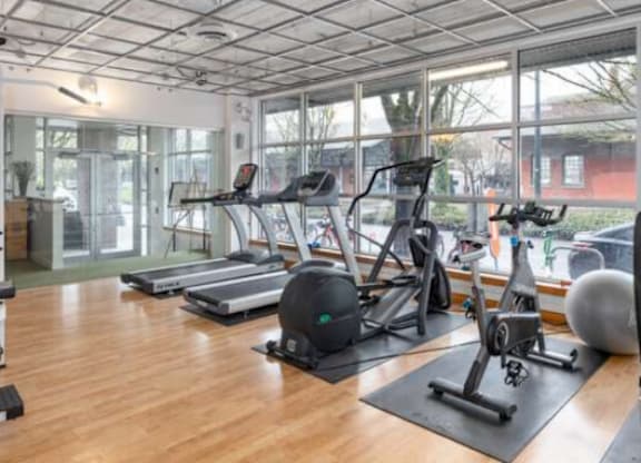 A gym with wooden floors and various exercise equipment.