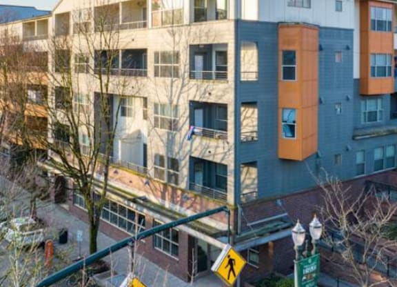 A pedestrian crossing sign is on a street in front of a multi-story building.